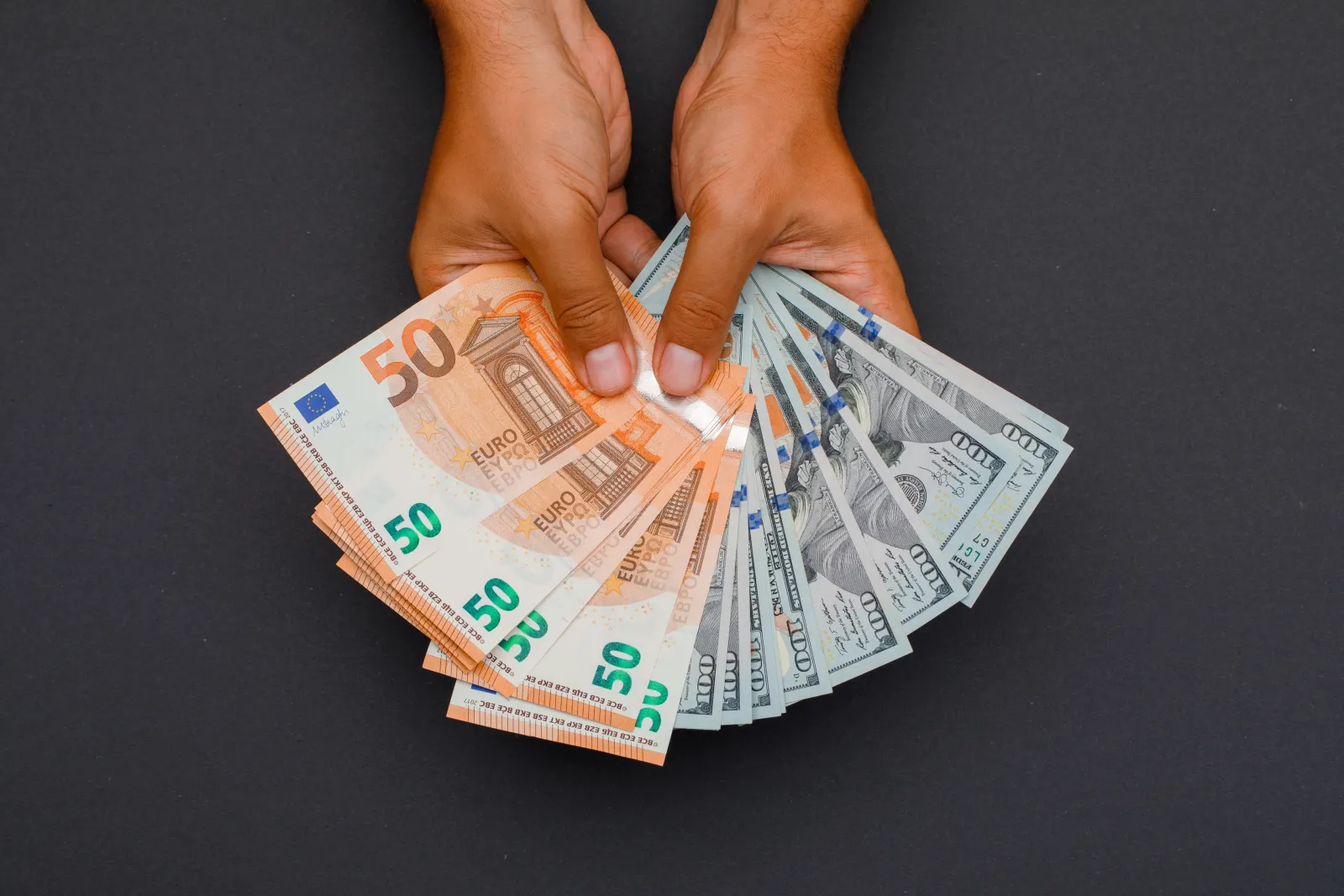 Hands holding euro and dollar notes