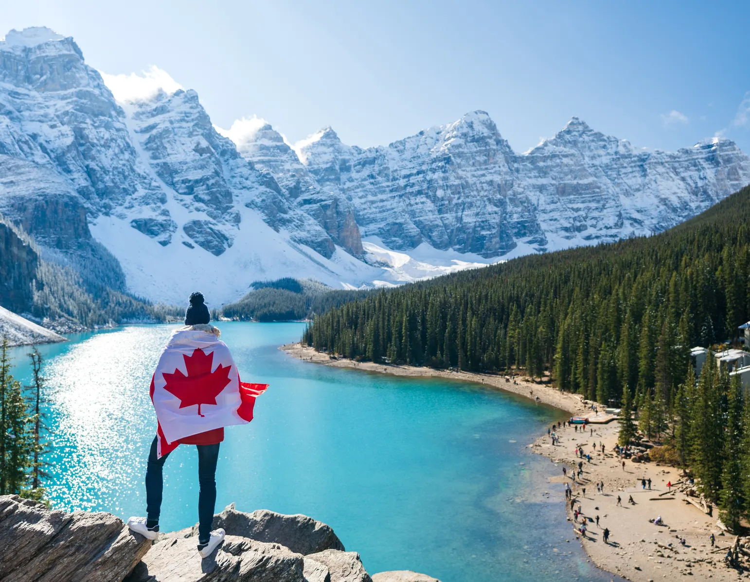 Hiker wrapped in a Canadian flag overlooking Moraine Lake